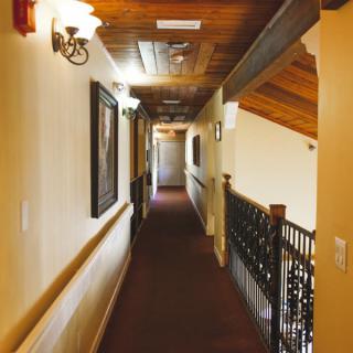 A well-lit hallway with a wooden ceiling and framed artwork on the walls.