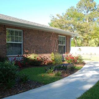 A brick house with a garden and sidewalk in front.