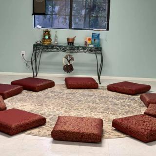 A serene indoor meditation space with cushions arranged in a circle on a rug.