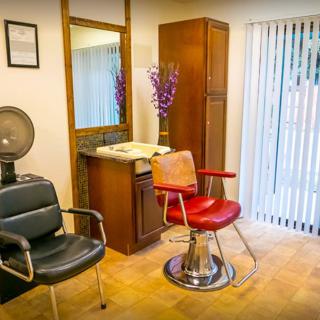A cozy salon interior featuring stylish chairs and a large mirror.
