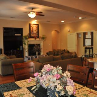 A cozy living room featuring a dining table with a floral centerpiece, sofas, and a fireplace.