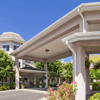 A view of a building entrance featuring columns and well-maintained landscaping under a clear blue sky.
