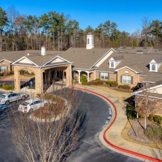 Aerial view of a residential building with a circular driveway surrounded by trees.