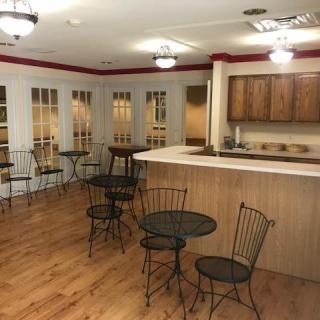 A cozy cafe interior with round tables, chairs, and a wooden counter with overhead lighting.