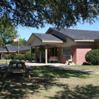 A school building with a picnic bench under a large tree.