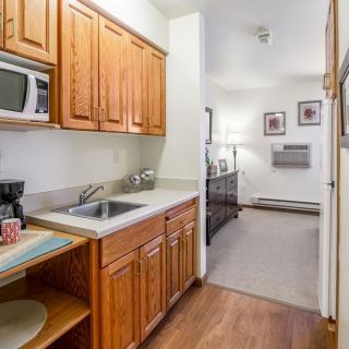 A compact kitchen area in an apartment with wooden cabinets, a sink, and a microwave.