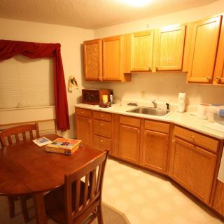 A cozy kitchen with wooden cabinets, a dining table, and chairs.