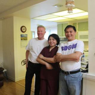 A group of three people standing together in a kitchen.