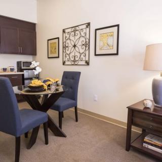 A cozy dining area with a small round table, two blue chairs, and modern decor.