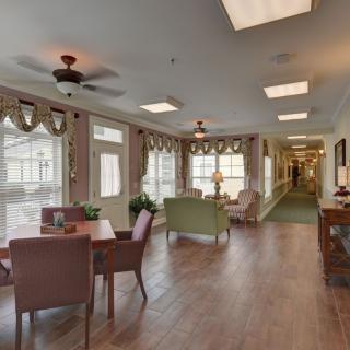 A cozy and well-lit interior space featuring a sitting and dining area with large windows, stylish decor, and a wooden floor.