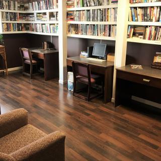 A cozy library with bookshelves, desks, and comfortable seating.