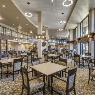 Spacious dining hall with modern lighting and neatly arranged tables and chairs.