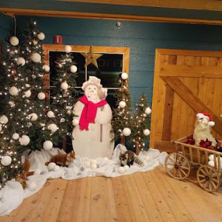A charming holiday display featuring a snowman and decorated Christmas trees.