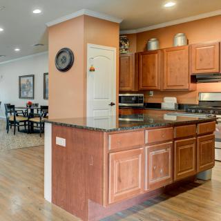 A modern kitchen with wooden cabinets and granite countertops, connected to an open dining area.
