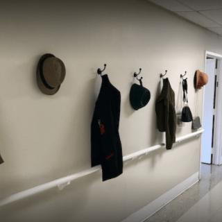 A hallway featuring various hats and coats hanging on hooks as wall decor.