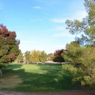 A scenic view of a golf course with lush greenery and trees under a clear blue sky.