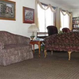 A cozy living room with sofas, chairs, a table, and a bookshelf.