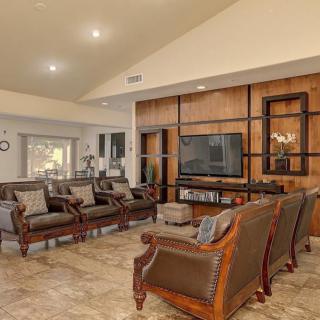 A spacious living room with elegant furniture and a television set against wood paneling.