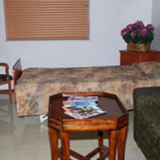 A cozy bedroom with a bed, wooden table, and flower arrangement.
