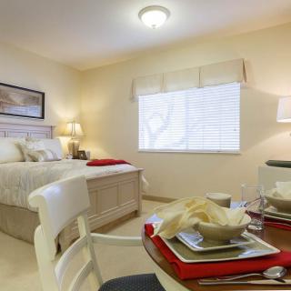 A cozy bedroom with a neatly arranged dining table set, featuring elegant decor and soft lighting.