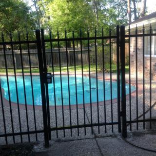 A fenced swimming pool in a backyard setting.