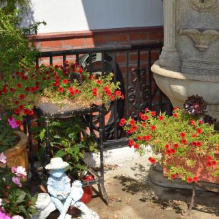 A charming garden corner featuring a small statue surrounded by vibrant flowers and potted plants.