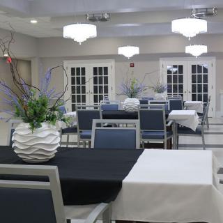 A modern dining area with tables and chairs arranged neatly, featuring decorative vases as centerpieces.