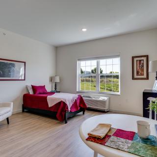 A cozy bedroom with a single bed, large window, and tasteful decor.