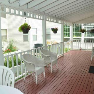 A cozy patio with white chairs and hanging plants under a pergola.