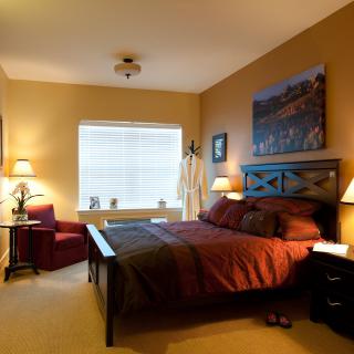 A cozy bedroom with warm lighting, featuring a bed and elegant furnishings.