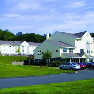 View of a residential building complex with a parking lot and surrounding greenery.