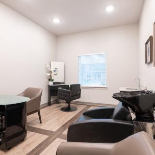 A modern hair salon interior with chairs, a sink, and ample lighting.