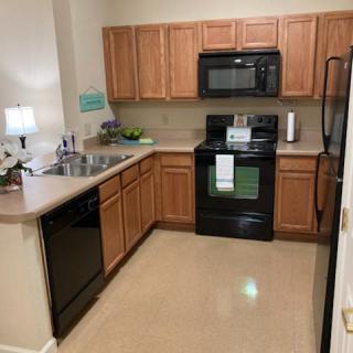 A modern kitchen with wooden cabinets and black appliances.