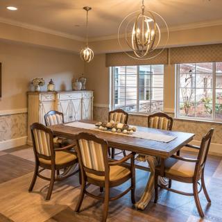 A cozy dining room with a wooden table and six chairs, featuring warm lighting and elegant decor.
