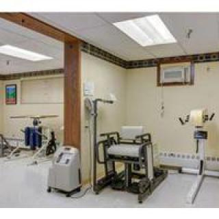 A therapy room equipped with various exercise machines and rehabilitation tools.