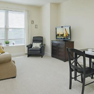 A cozy living room with a sofa, chair, television, and dining table.
