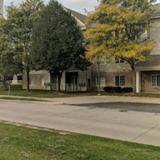 A view of a residential building bordered by trees and a quiet street, showcasing the autumn colors.