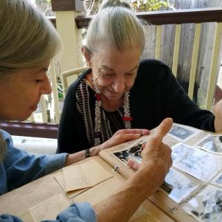 Two elderly women looking through a photo album together.