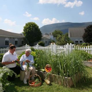 Two people sitting in a community garden with a scenic mountain view.