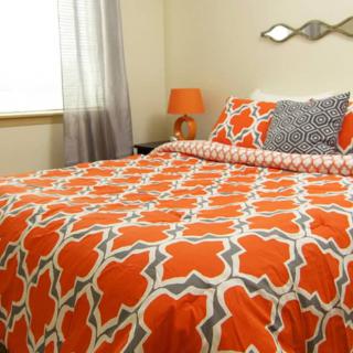 A well-decorated bedroom featuring orange patterned bedding and coordinated decor.