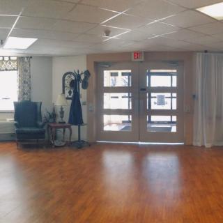A spacious lobby area with wooden flooring and glass doors.