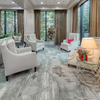 A modern living room with elegant furnishings, featuring armchairs, large windows, and soft lighting.