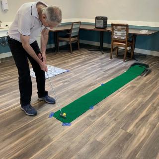 A person practicing mini golf on an indoor putting green.