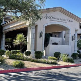 Front entrance of a building with landscaping and palm trees in a sunny setting.