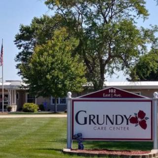 A sign for Grundy Care Center in front of a building with surrounding greenery.