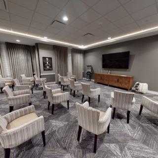 A modern conference room with arranged chairs and a large television.