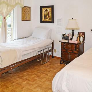 A cozy bedroom with two beds, a wooden floor, and a window letting in natural light.