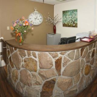 A welcoming reception area featuring a stone wall, decorative flowers, and a large clock.