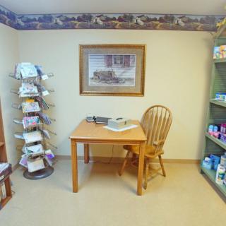 A small office with a wooden desk and chair, surrounded by shelves filled with books and supplies.