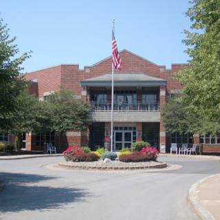 A well-maintained public building surrounded by greenery and colorful flowers.